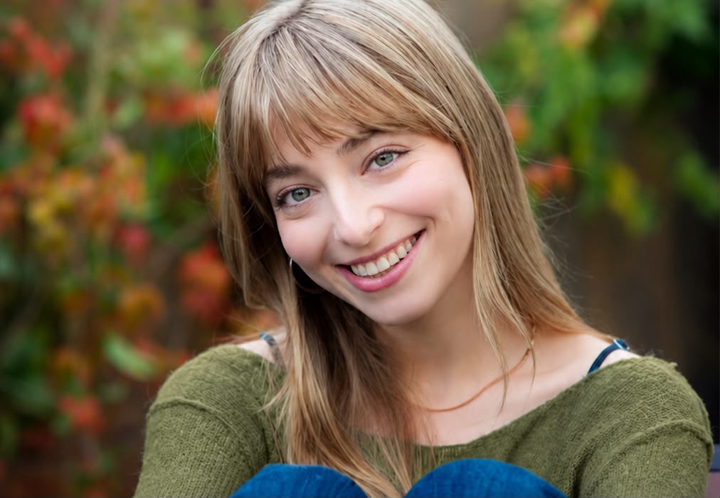 Lee Kedem smiling, autumn foliage behind her